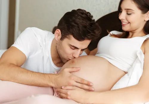 Un futuro papà bacia la pancia della sua compagna