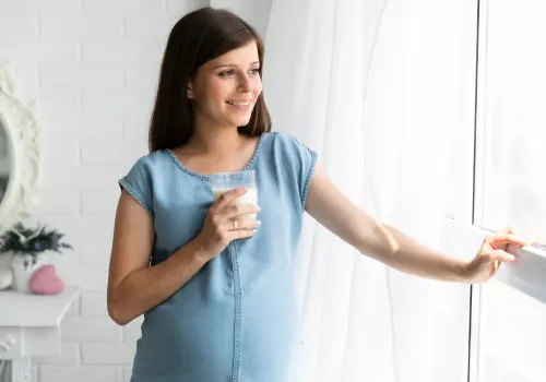 Donna incinta con in mano un bicchiere di latte